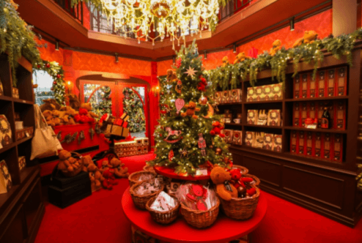 빨간 상점 안 둘레로 크리스마스 갖가지 소품이 놓여있고 가운데 빨간 작은 크리스마스 트리
