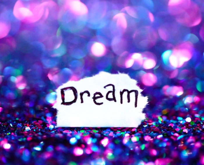 보석처럼 빛나는 물체 위에 Dream이라는 단어가 흰 종이에 적힌 모습