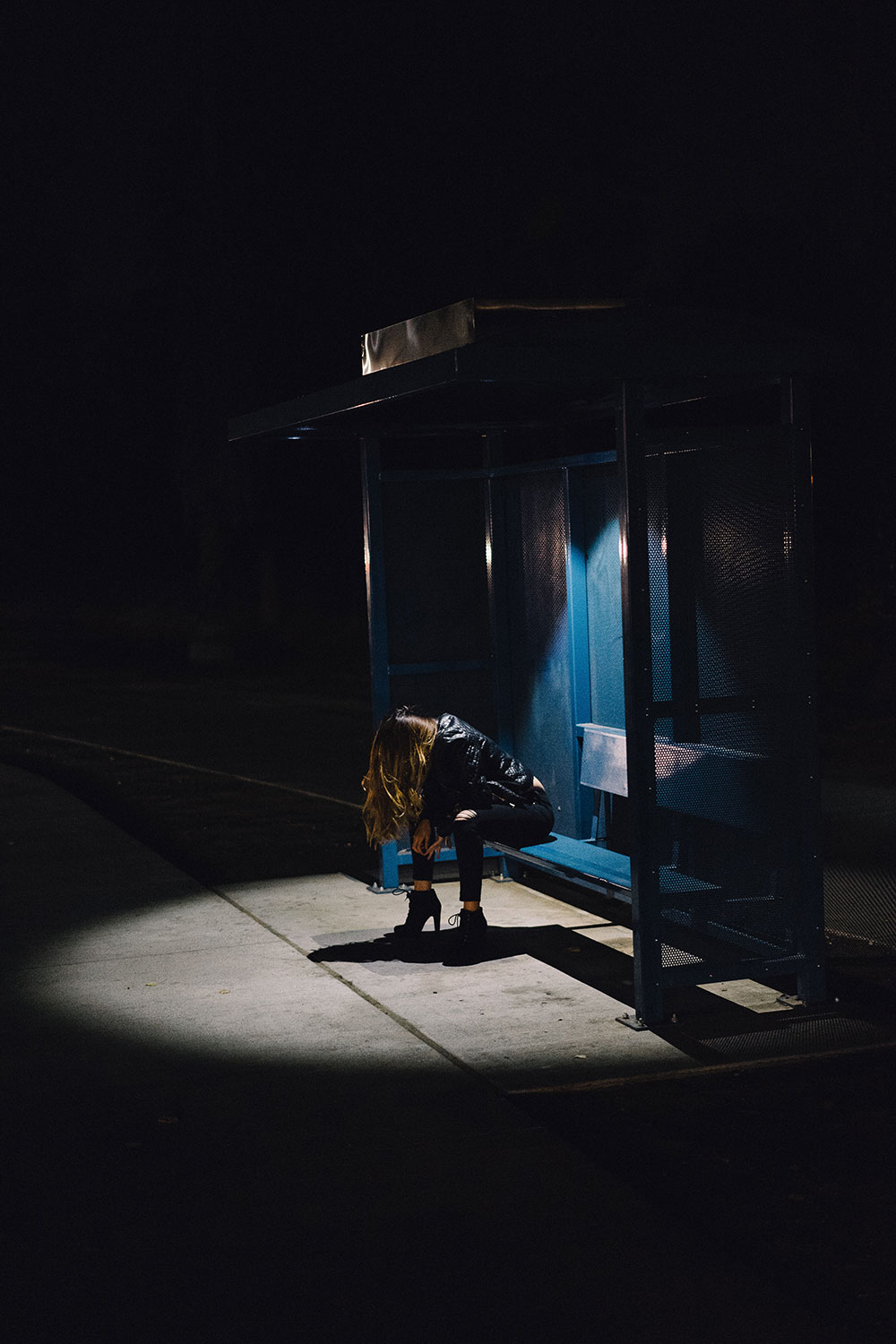 어두운 버스정류장에서 지쳐있는 여성