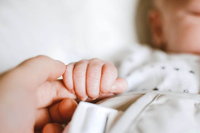 검지 손가락을 잡고 있는 아기 손이 있는 사진