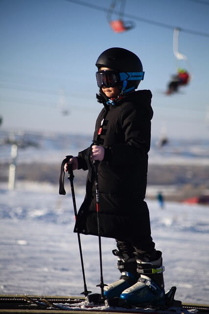 아이가 스키장비를 갖추고 스키장에 서있는 모습
