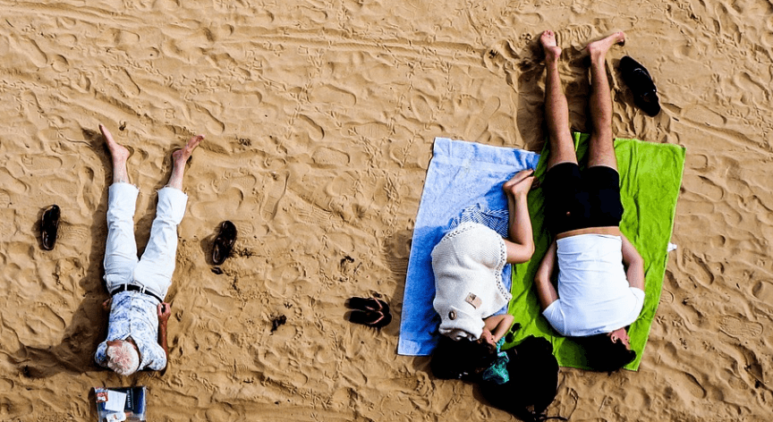 모래사장 위에서 남성과 여성이 잠을 자고 있는 모습
