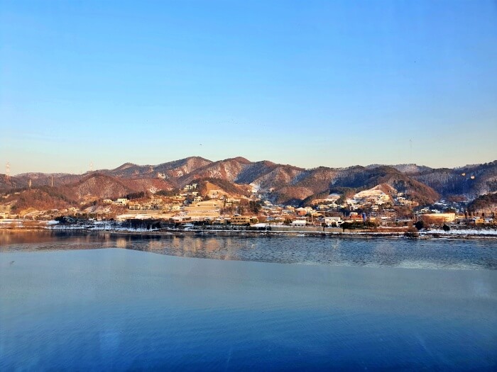 라온숨 안에서 밖을 바라본 눈내린 산과 강이 조화를 이룬 풍경사진