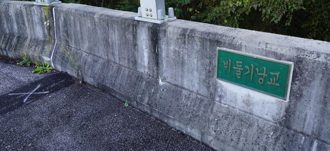 우측 콘크리트 난간벽에 붙은 비둘기낭교라는 다리 이름표&#44; 녹색 바탕에 흰글씨&#44;