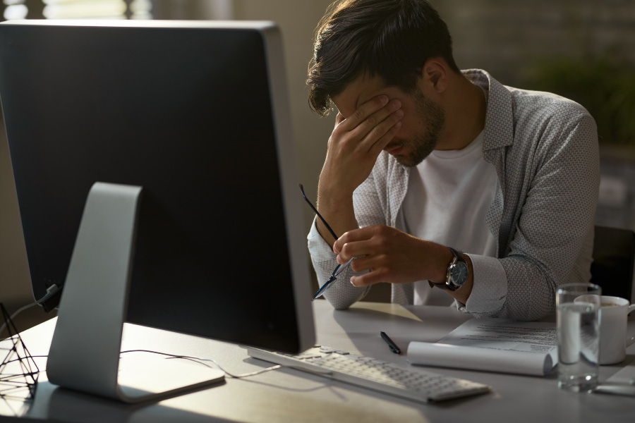 exhausted-businessman-holding-his-head-pain-while-working-desktop-pc-office-900