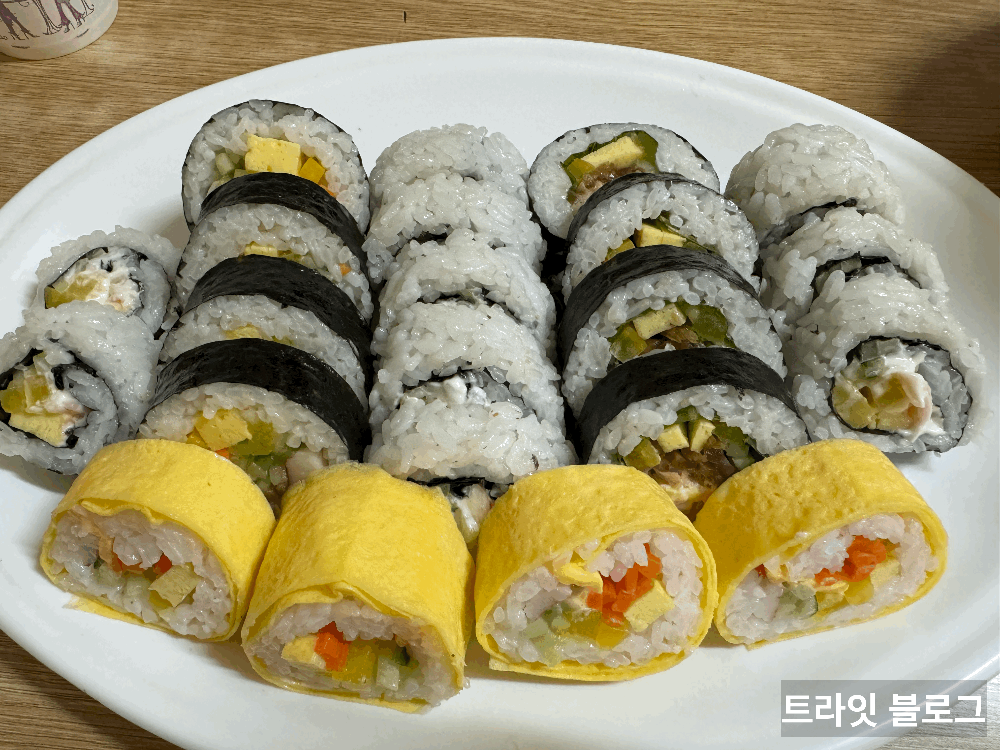 모둠이김밥
누드김밥과 계란 덮은 김밥과 다른 김밥들이 흰 접시에 올려져 있다.
