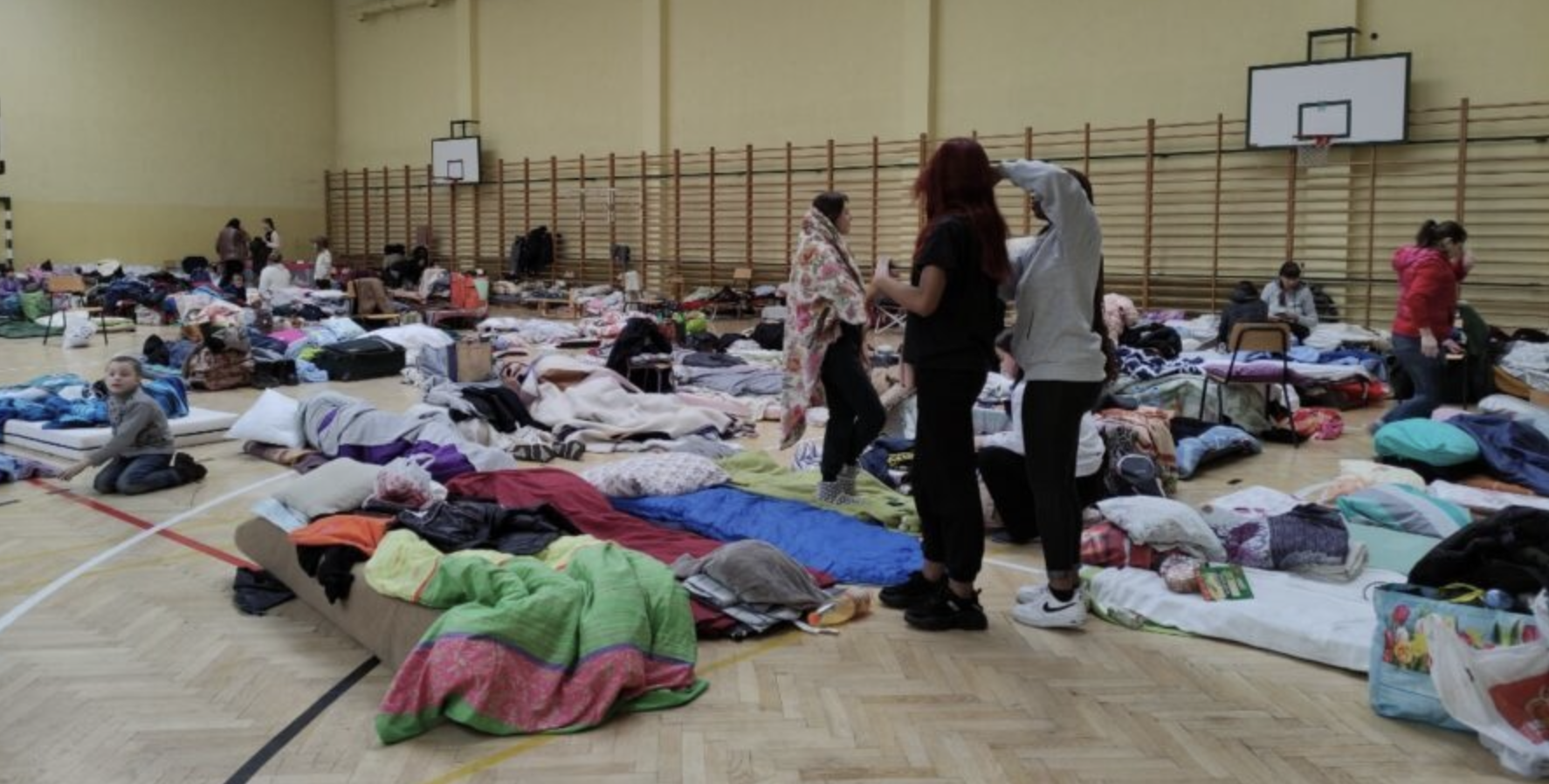 우크라이나 피란민들이 고등학교 체육관에서 임시거처로 지내는 모습, 마룻바닥에 얇은 매트리스를 짤고 담요를 덮고 누워있다.