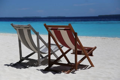 바닷가 모래 사장에 나란히 있는 의자 두 개