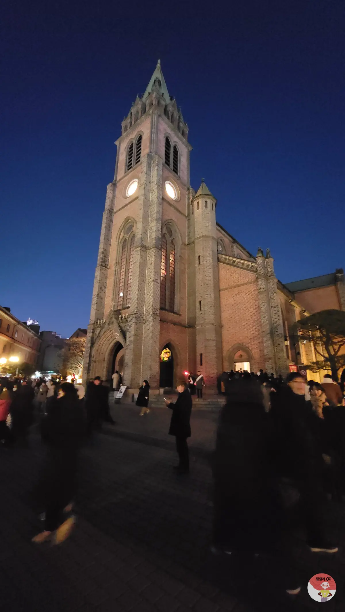 해질녘 붉은 빛 속에 고딕 양식 첨탑과 아치형 창이 돋보이는 명동대성당 본당 건물 모습