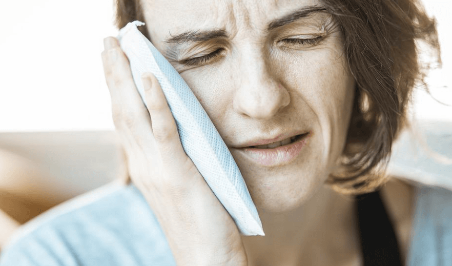 치통으로 얼음 팩을 볼에 대고 있는 여성