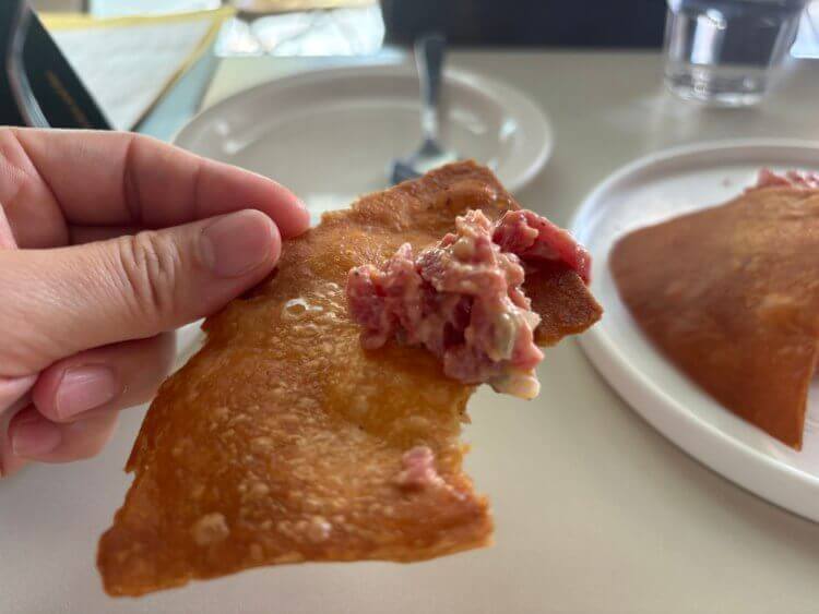 육회타르타르가 올려진 튀긴 또띠아를 들고 있는 모습