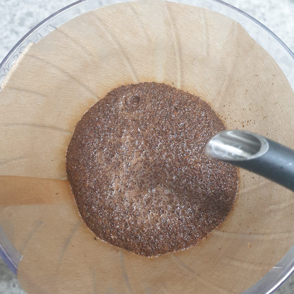 황색 필터 안에 담긴 부풀어 오른 커피 파우더. 중간 중간 이산화탄소가 빠져나간 구멍이 보인다.