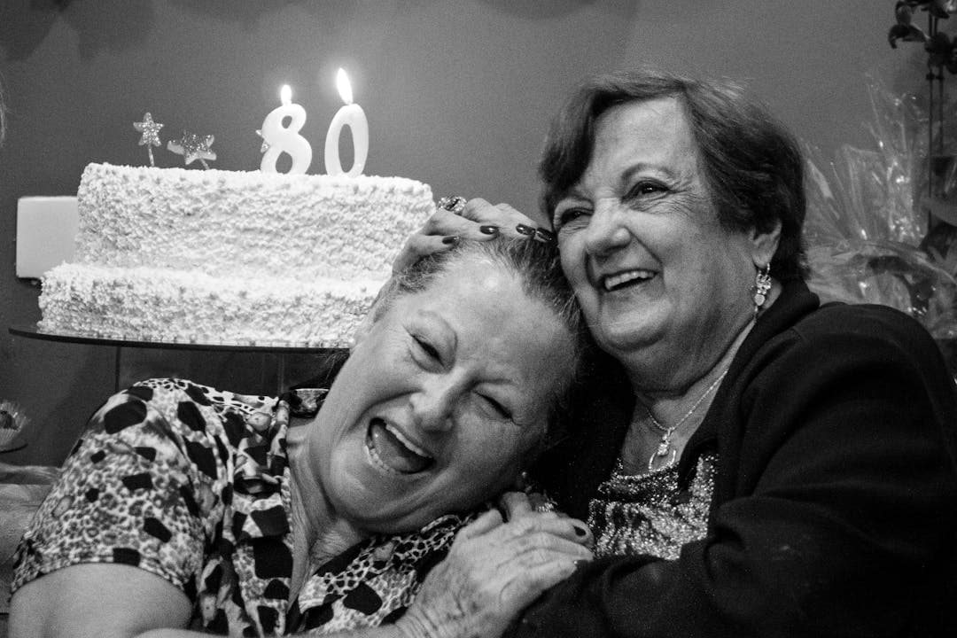 80번째 생일을 함께 축하하며 기뻐하는 두 여성 노인