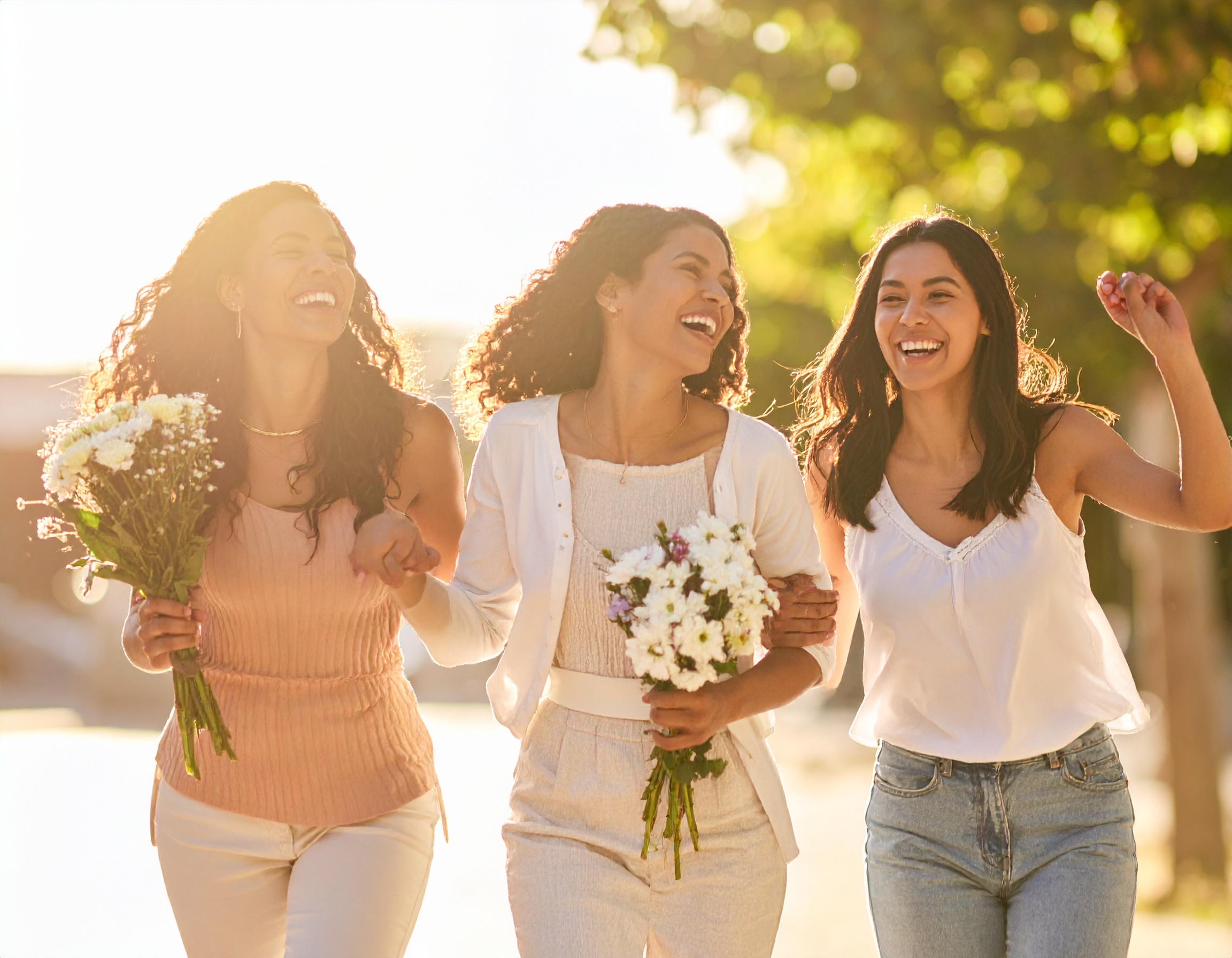꽃을 들고 웃으며 걷는 세 여성의 모습