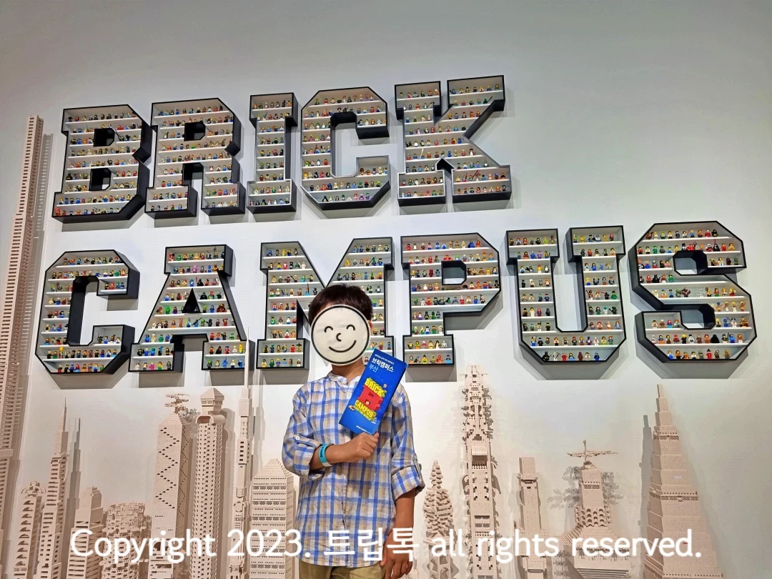 브릭 캐릭터들로 빼곡히 채운 브릭캠퍼스 영문앞에 한 아이가 서있다