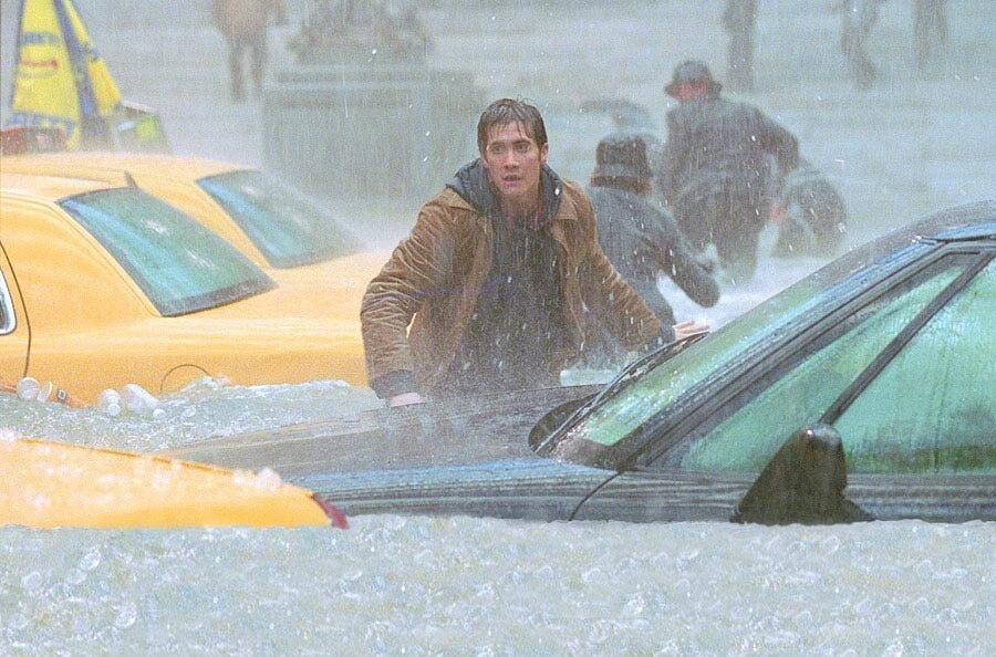 샘 홀이 물로 가득찬 거리의 자동차 사이를 걷고 있는 모습