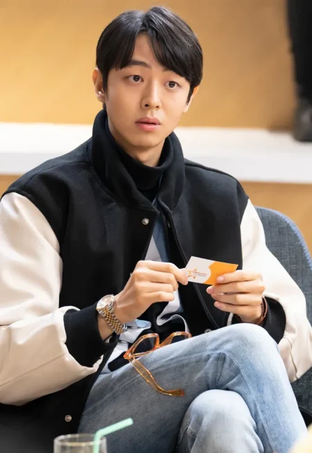 어느 실내의 쇼파에서 청바지에 검은 자켓을 입고 앉아 두손에 명함을 들고 있는 드라마 7인의 탈출의 한경수 캐릭터
