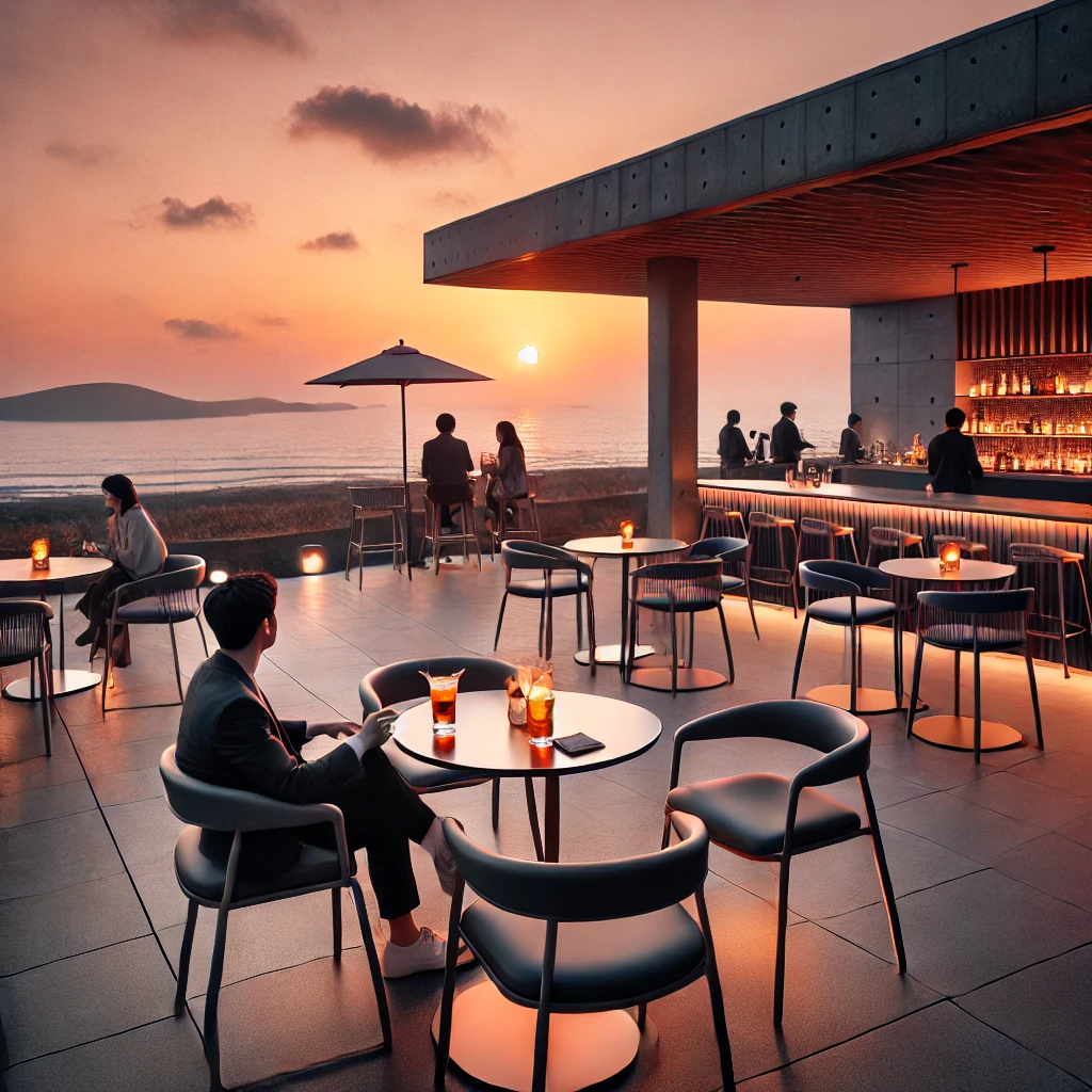 제주도 바다가 내려다보이는 세련된 옥상 카페. 현대적인 가구로 꾸며진 테라스에서 손님들이 음료를 즐기며 바다 위로 지는 노을을 감상하고 있음. 분위기는 세련되고 편안하며, 저녁이 되면서 따뜻한 조명과 함께 하늘이 오렌지와 분홍빛으로 물드는 아름다운 배경을 연출하고 있음.