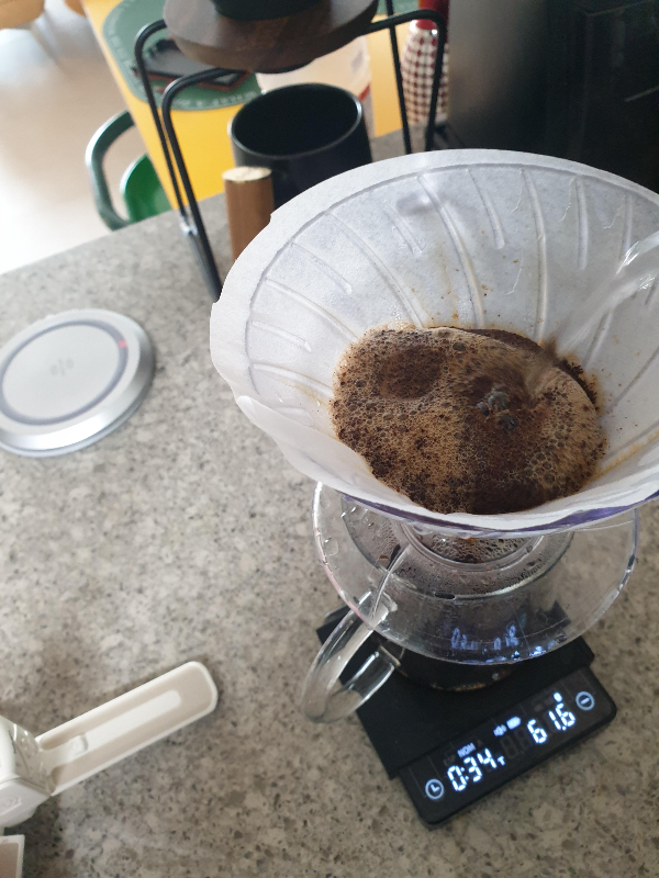저울은 34초에 61.6g을 가르키고 있다. 드리퍼에 물을 붓는 모습이 보인다.