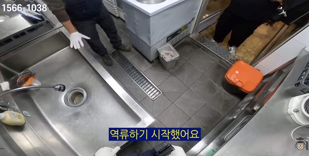식당 주방 바닥 트렌치와 배수구 주변에 물이 차오르며 역류 증상을 확인하는 장면