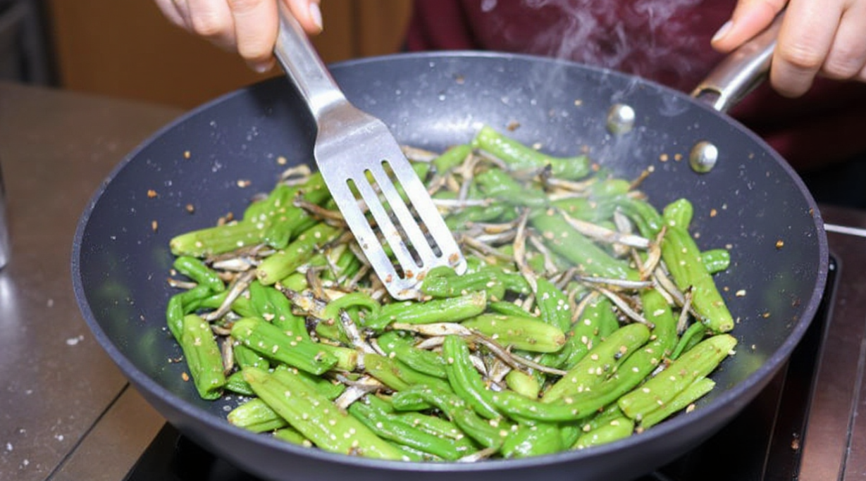 인 양념에 멸치와 꽈리고추를 넣고 주걱으로 빠르게 뒤섞어 양념을 입히고 있는 모습