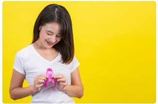 유방암 생존자가 유방암의 상징인 핑크 리본을 보며 웃고 있다.