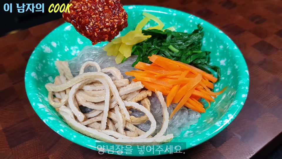 그릇에 당면과 고명을 담고 양념장을 올리는 장면