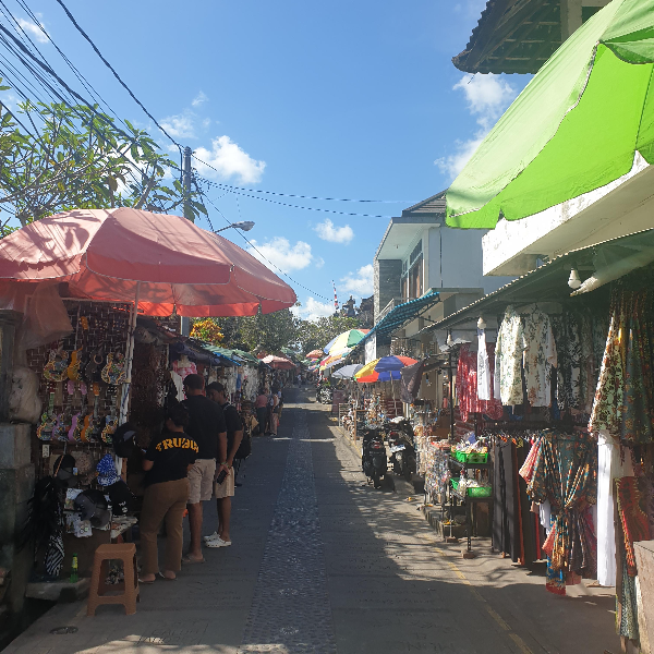 파란하늘 아래 이어진 가게 파라솔과 어닝들. 가게에 옷들이 걸려있다.