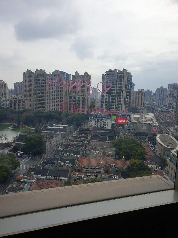 창 밖 하늘은 어둡지만 빌딩과 연못 그리고 낮은 집들이 보이는 뷰