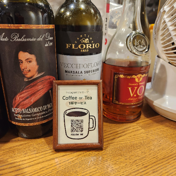 와인과 꼬냑 병과 후기 댓글 안내문이 놓여 있다. 후기를 쓰면 커피나 티 한 잔 제공