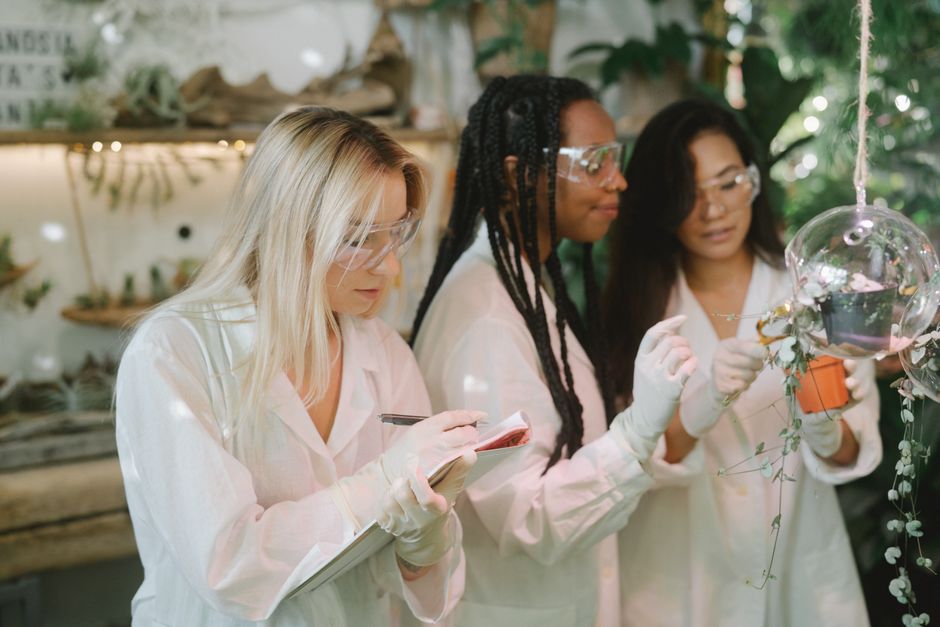 Three women scientists conducting plant research in a modern laboratory setting.