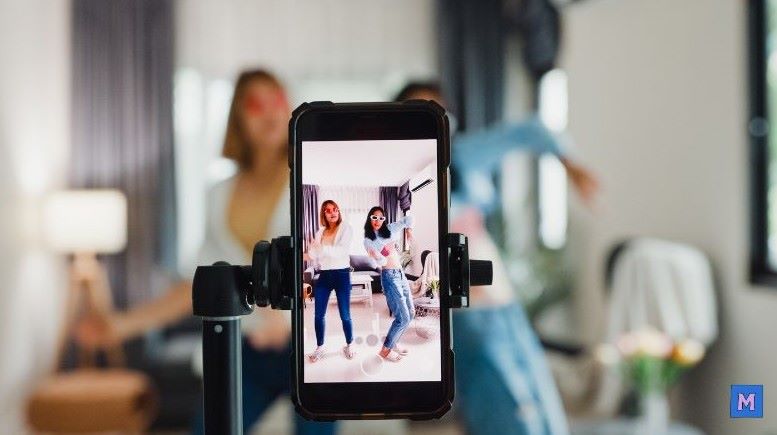 스마트폰으로 두 명의 여성이 댄스나 챌린지를 촬영하는 모습, 틱톡 콘텐츠 제작 과정을 보여주는 실제 사진 via Canva