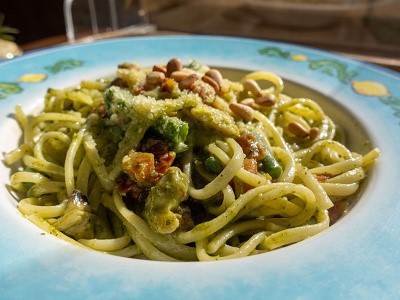 초록색의 파스타가 파란색 접시에 담겨져 있다.