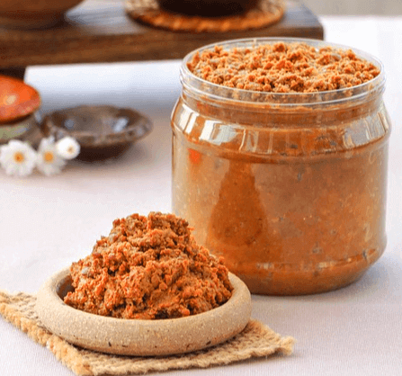 커다란 투명 플라스틱 통에 된장이 가득 담겨 있고 오른쪽에는 된장이 담긴 그릇이 있다.