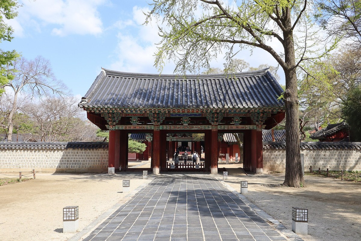 The red entrance gate of Gyeonggijeon Shrine in Jeonju seen from a stone-paved path
