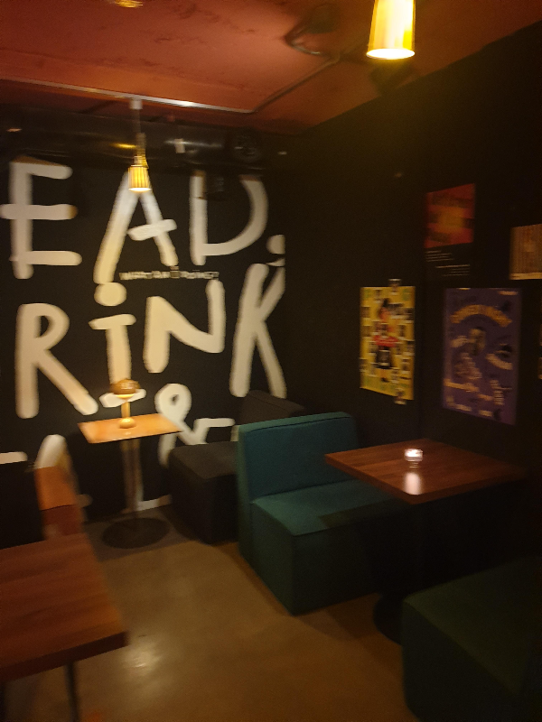 블랙 조닝. 뒷편 흰색 커다란 글자가 써있고 우측엔 사진이 가득 걸려있다.