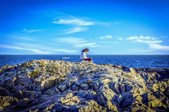 여성이 바닷가에서 책을 보고 있는 모습