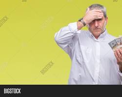 Frustrated person holding head with money in background