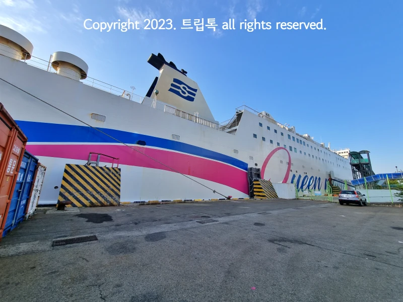 파란 하늘과 파란색과 분홍색 긴 띠가 그려진 퀸메리호의 모습