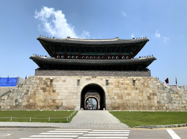 맑은 하늘 아래 웅장하게 서 있는 수원화성 북문 장안문 정면 모습&#44; 돌길과 성곽 구조가 인상적임