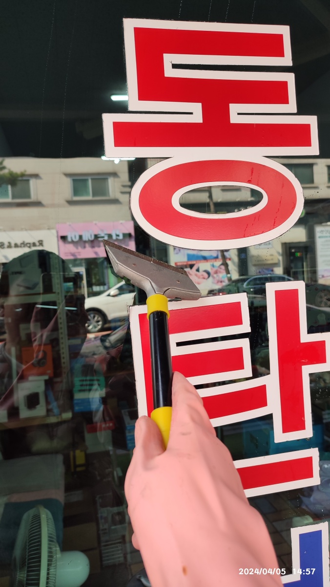 스크래퍼로 문에 붙은 스티커, 시트지 제거 중