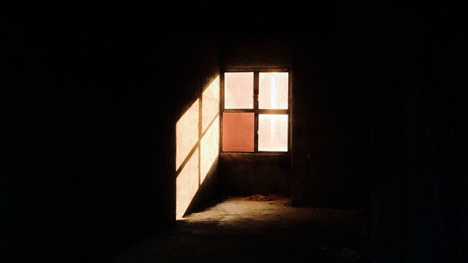 Sunlight casting dramatic shadows through a window in a dark room.