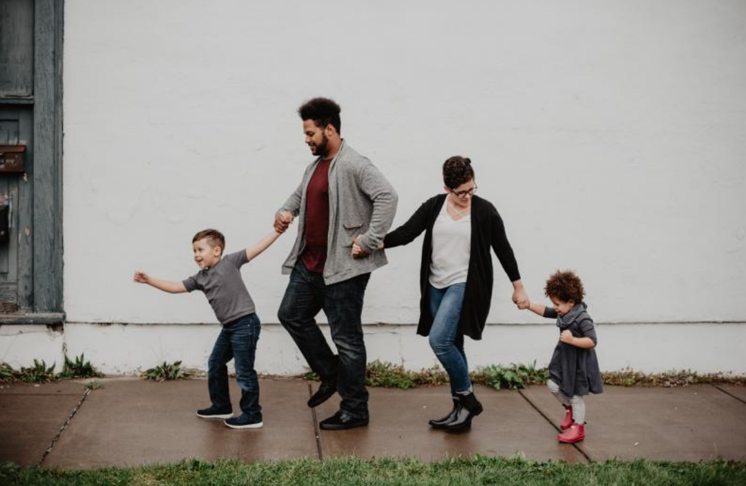 4인 가족이 서로 손을 잡으며 즐거워 하고 있다.