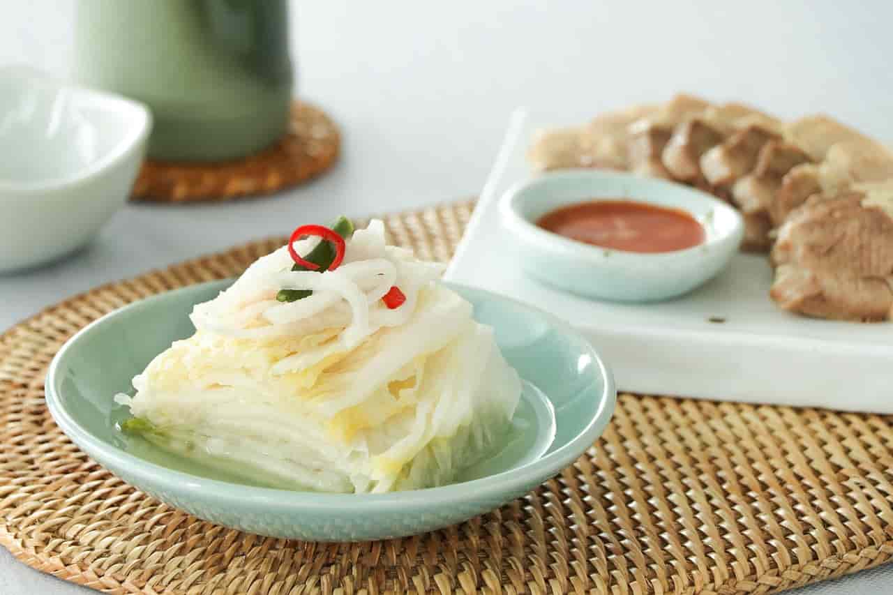 백김치와 수육 한 상차림. 시원하고 깔끔한 백김치와 부드러운 삶은 돼지고기, 새콤한 소스가 어우러진 전통 한식 반찬.