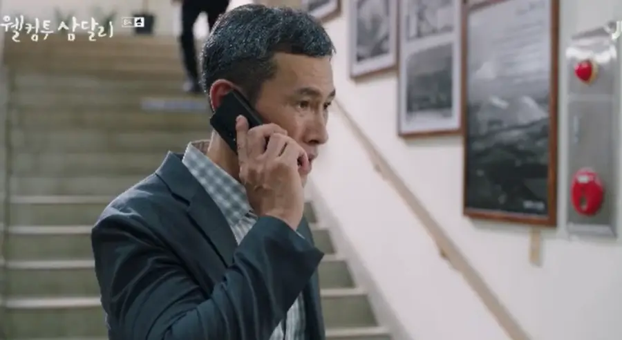 웰컴투삼달리- 양복입고 머리가 히끗한 아저씨가 오른손에 핸드폰을 들고 통화하는 모습
