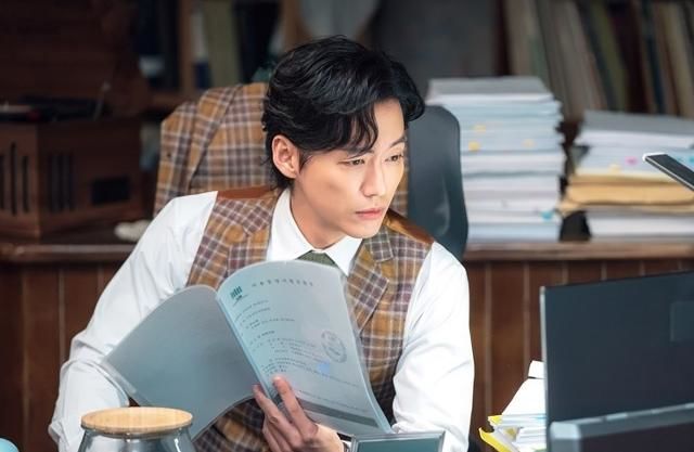 남자주인공이 책상위에서 열심이 일을 하는 모습