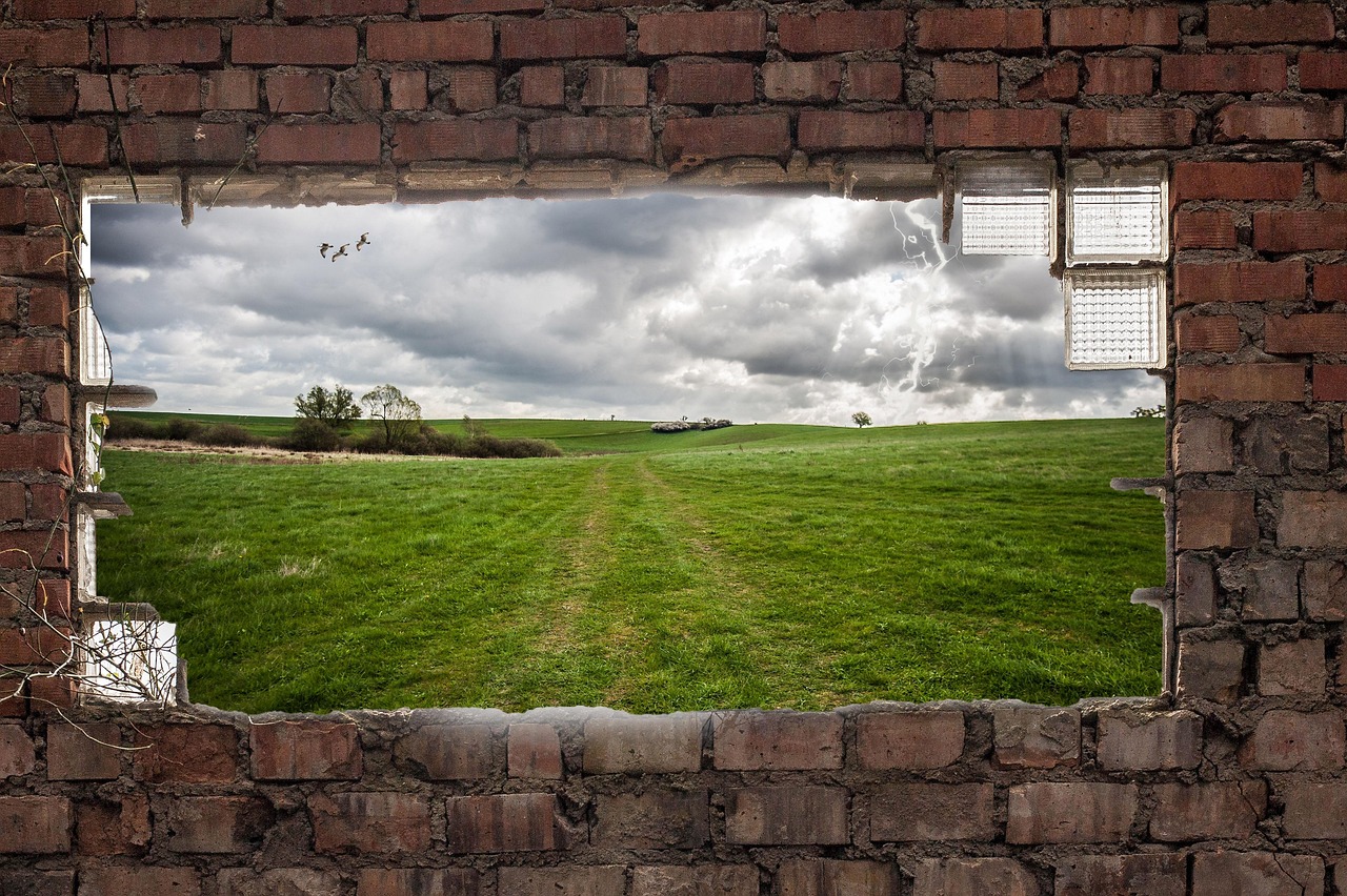 벽돌 건물의 액자처럼 뚫린 창 밖으로 펼쳐진 초원이 있는 사진