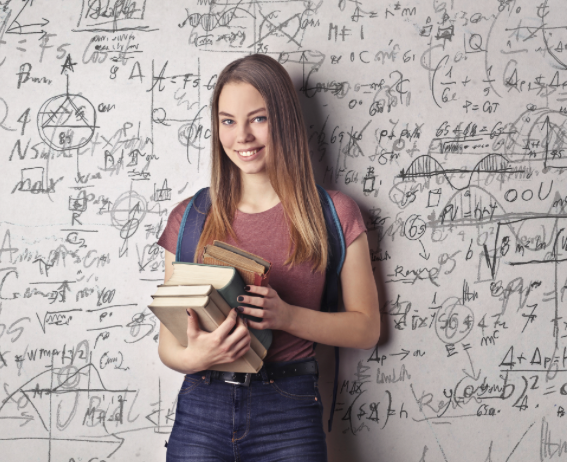 책을 들고 가방을 매고 빼곡히 필기된 칠판에 기대고 있는 여자