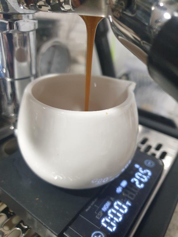 흰 에스프레소 잔에 일자로 떨어지는 에스프레소.