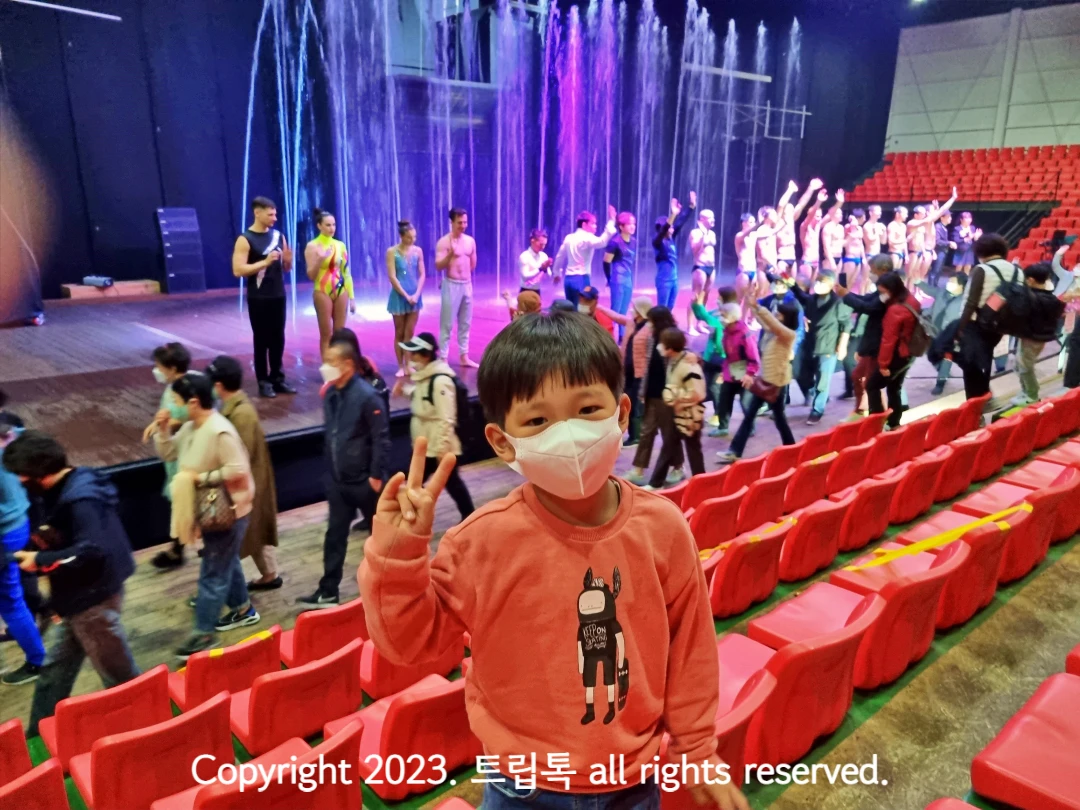 무대에서 인사하는 충련진과 분수와 그 앞의 아이